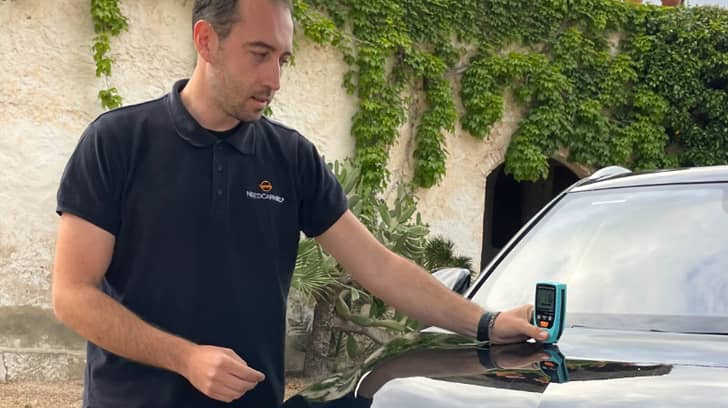 Técnico de NeedCarHelp midiendo el espesor de la pintura de un coche durante una revisión